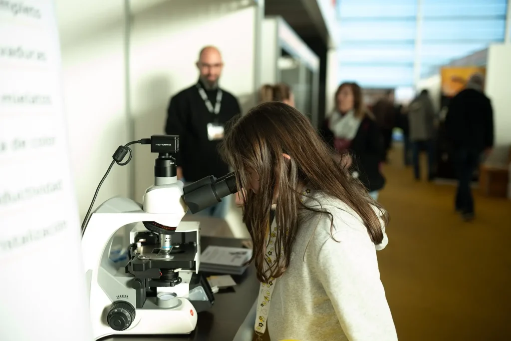 Una joven mira por un microscopio en la feria.