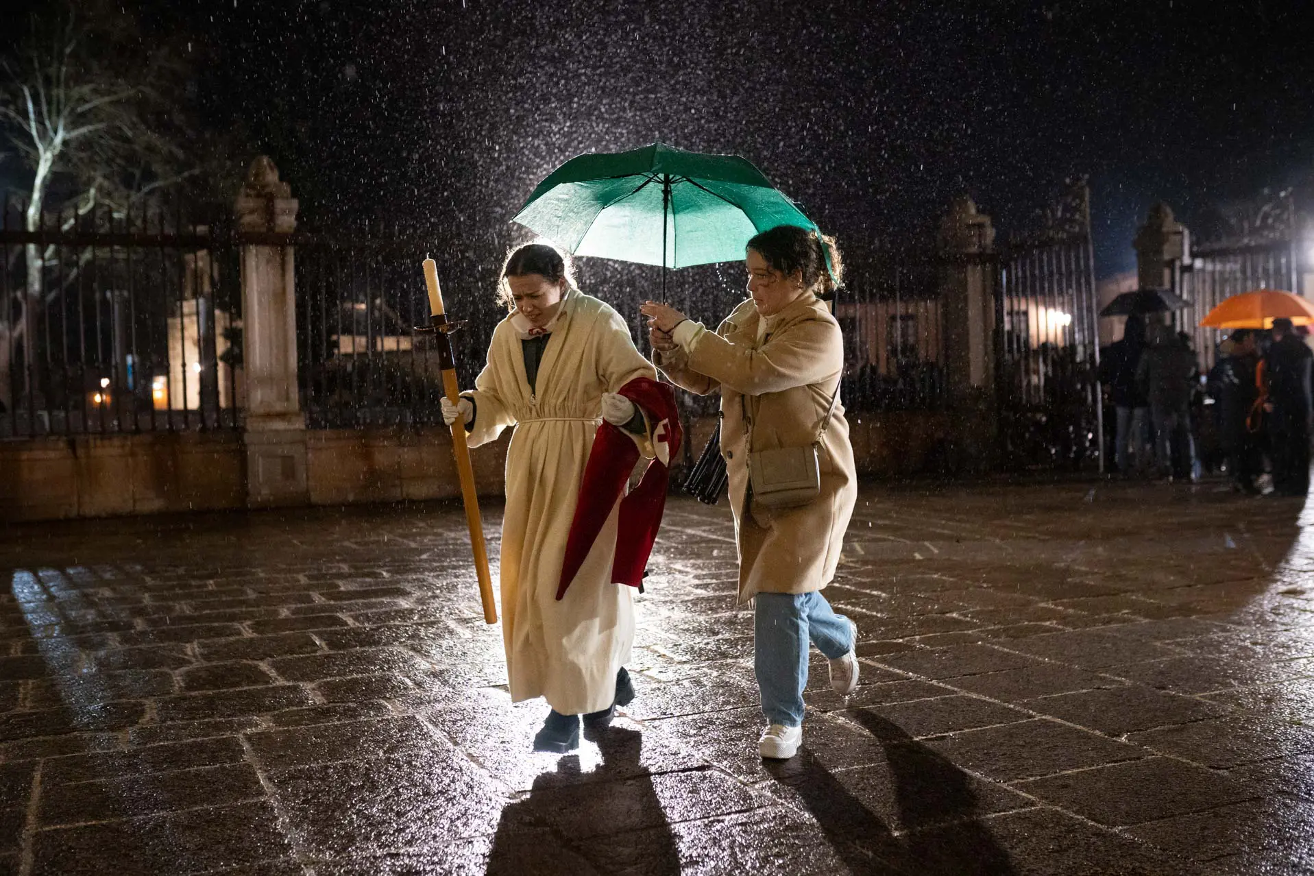 Una cofrade y su acompañante corren a resguardarse de la lluvia en el atrio de la Catedral. Foto Emilio Fraile.