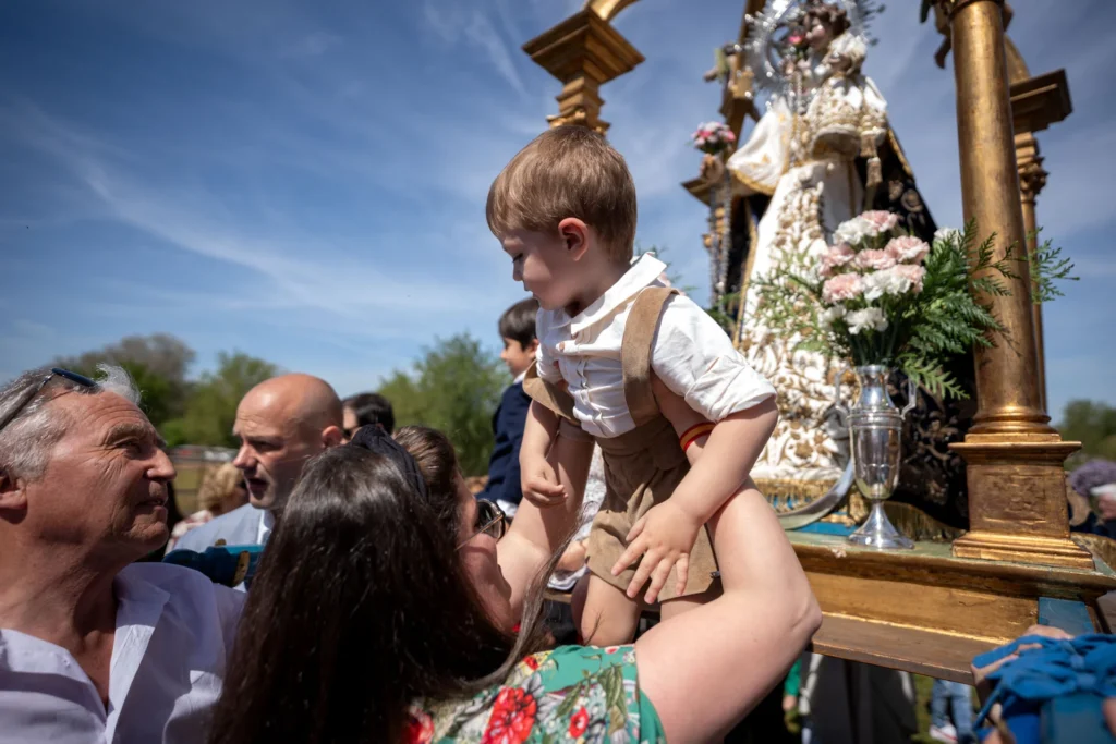 Una mujer sube a un niño a las andas de la Virgen del Olmo. Foto Emilio Fraile.