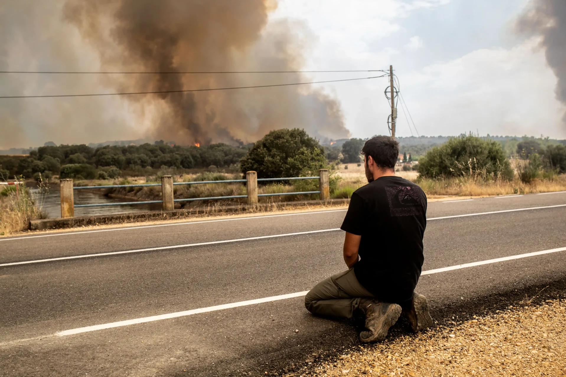 Un joven arrodillado ve el fuego acercarse a Pumarejo de Tera. Foto Emilio Fraile.