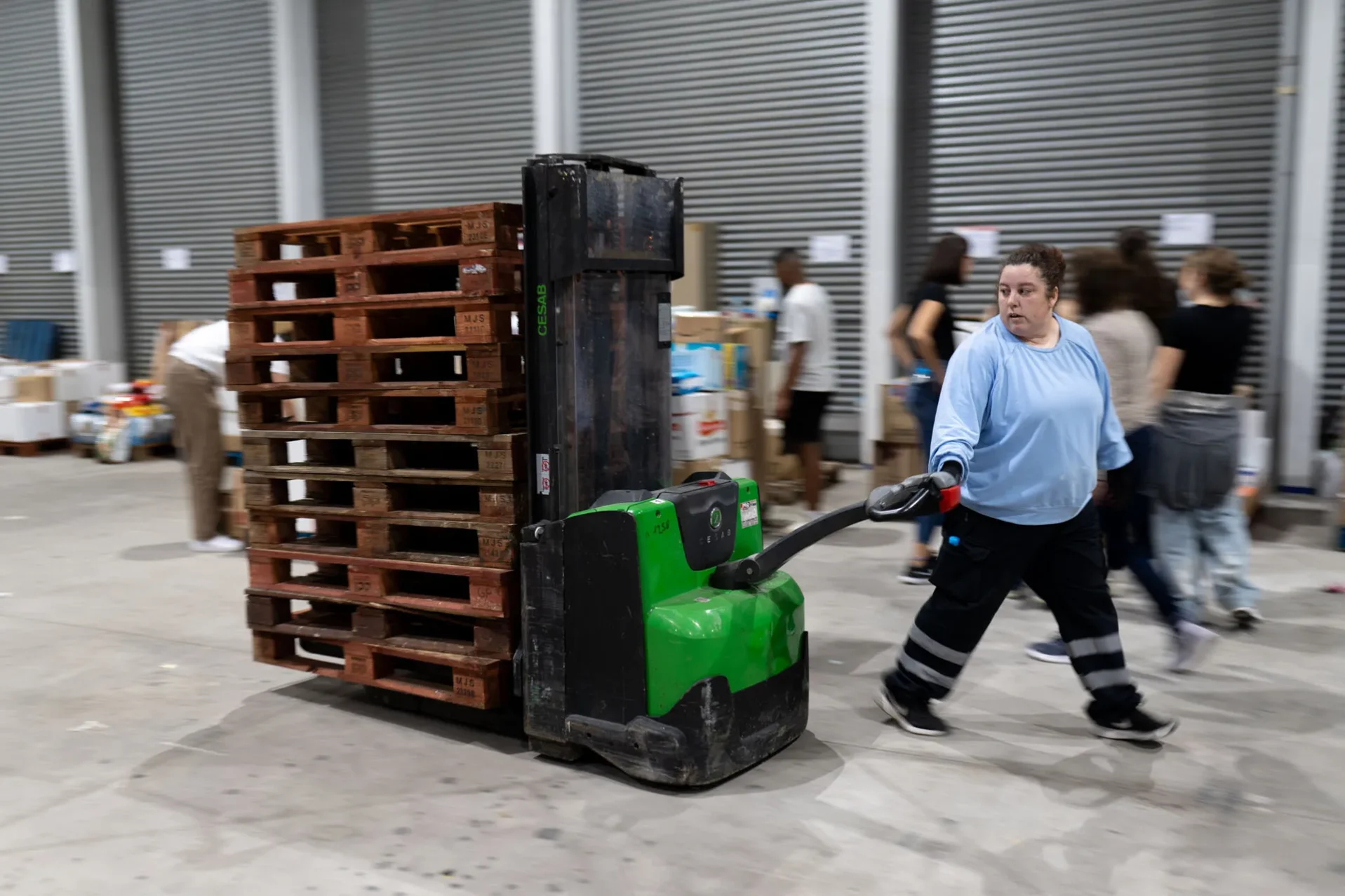 Una voluntaria tira de una carretilla cargada de palés. Foto Emilio Fraile.