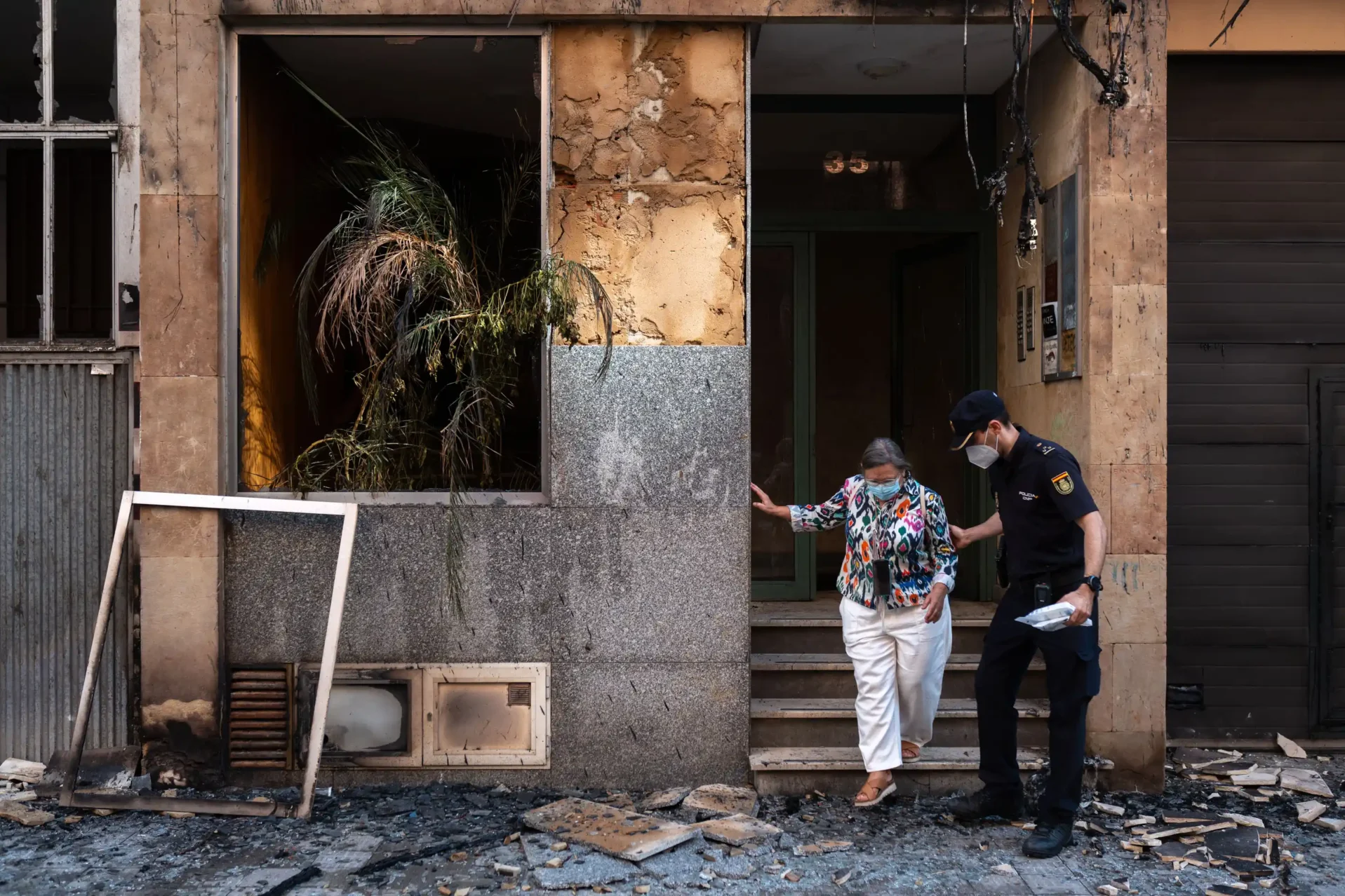 Un policía ayuda a una vecina a salir de uno de los portales afectados por el incendio. Foto Emilio Fraile.